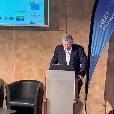 Un homme en costume foncé donnant un discours derrière un podium lors d'un événement sur l'hydrogène.