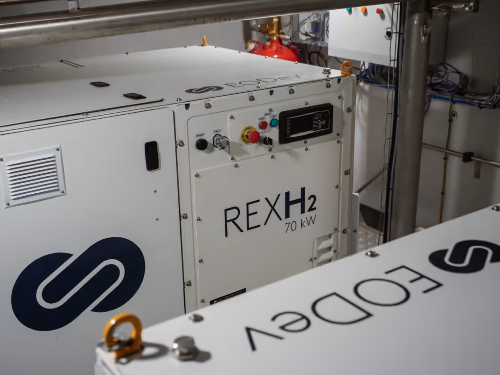 Générateur blanc REXH2 de 70 kW dans une salle technique avec des câbles et un extincteur en arrière-plan.