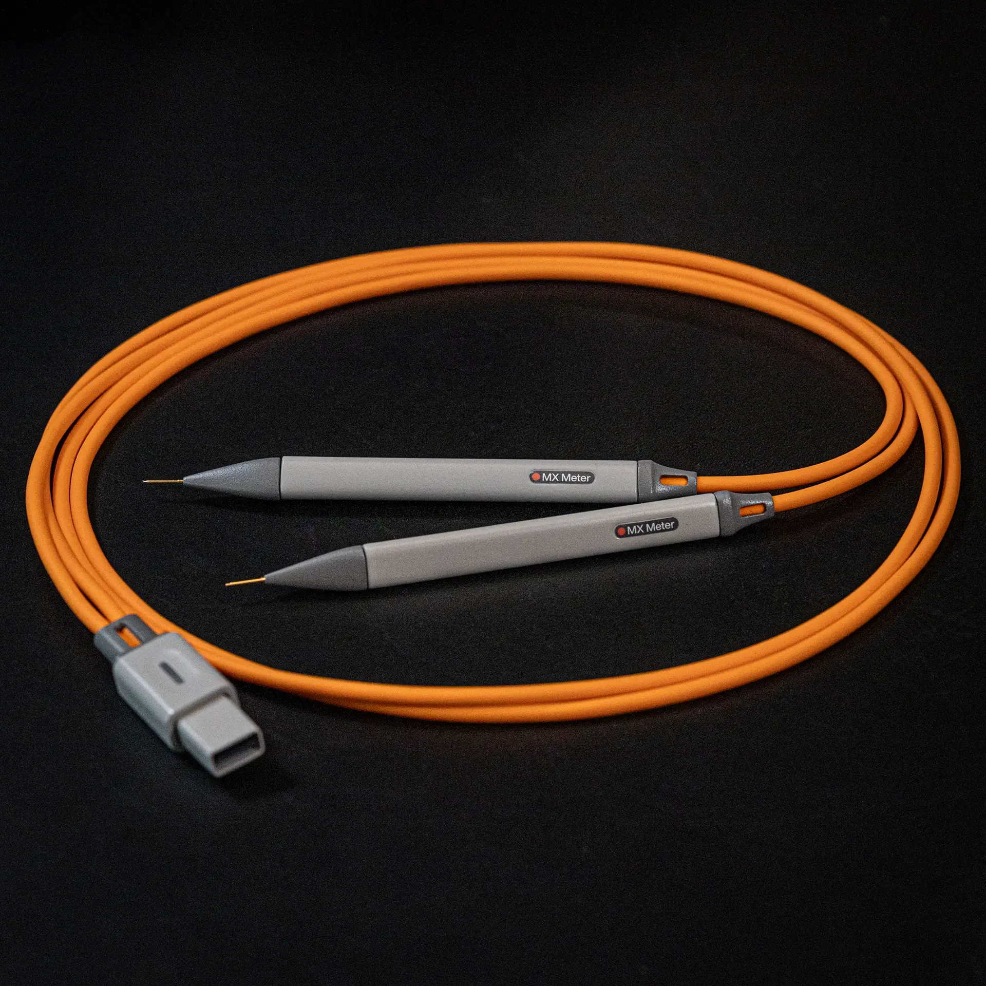 Orange probe cable with two gray pointed tester probes labeled MX Meter on a black background.