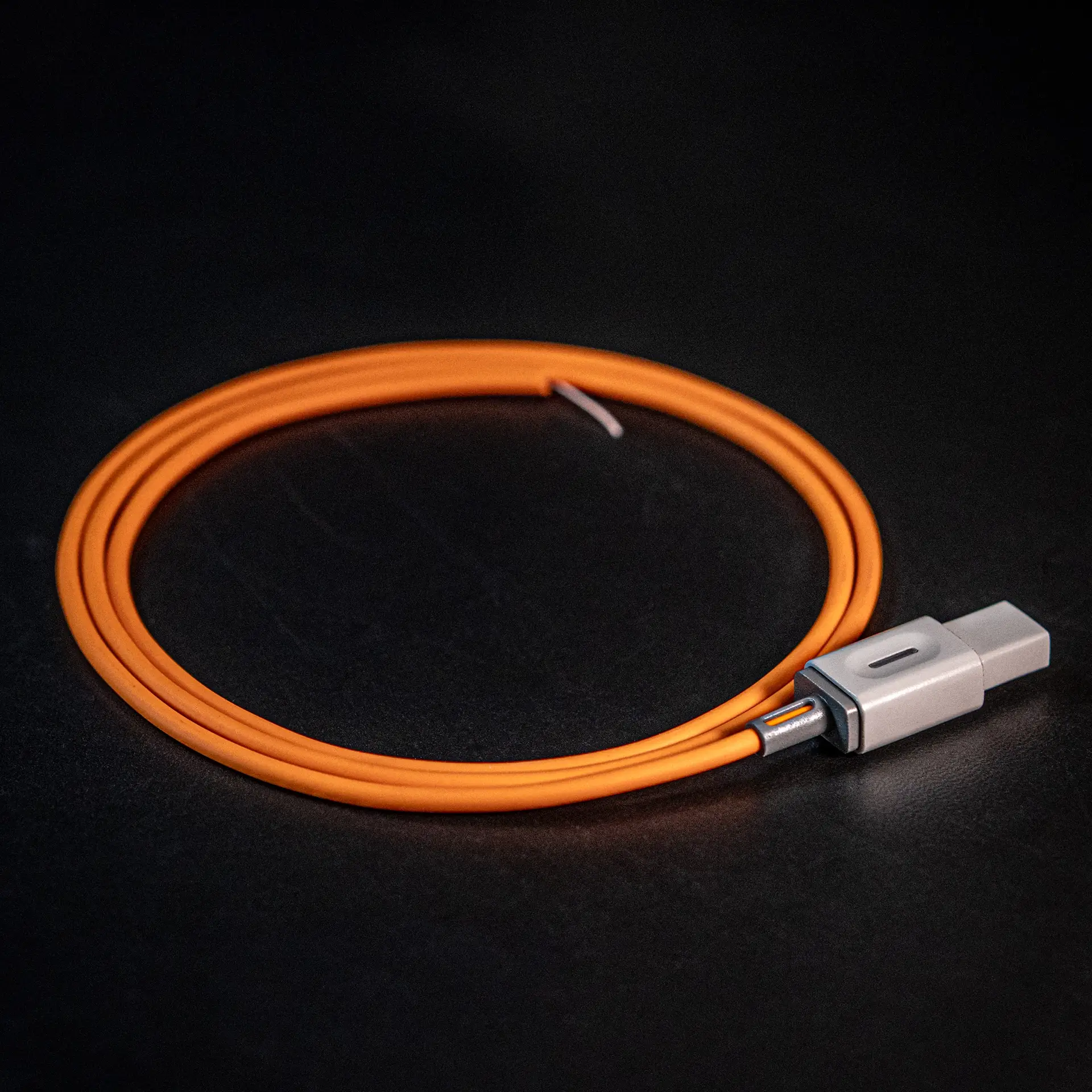 Coiled orange USB-C charging cable with a gray connector on a dark surface.