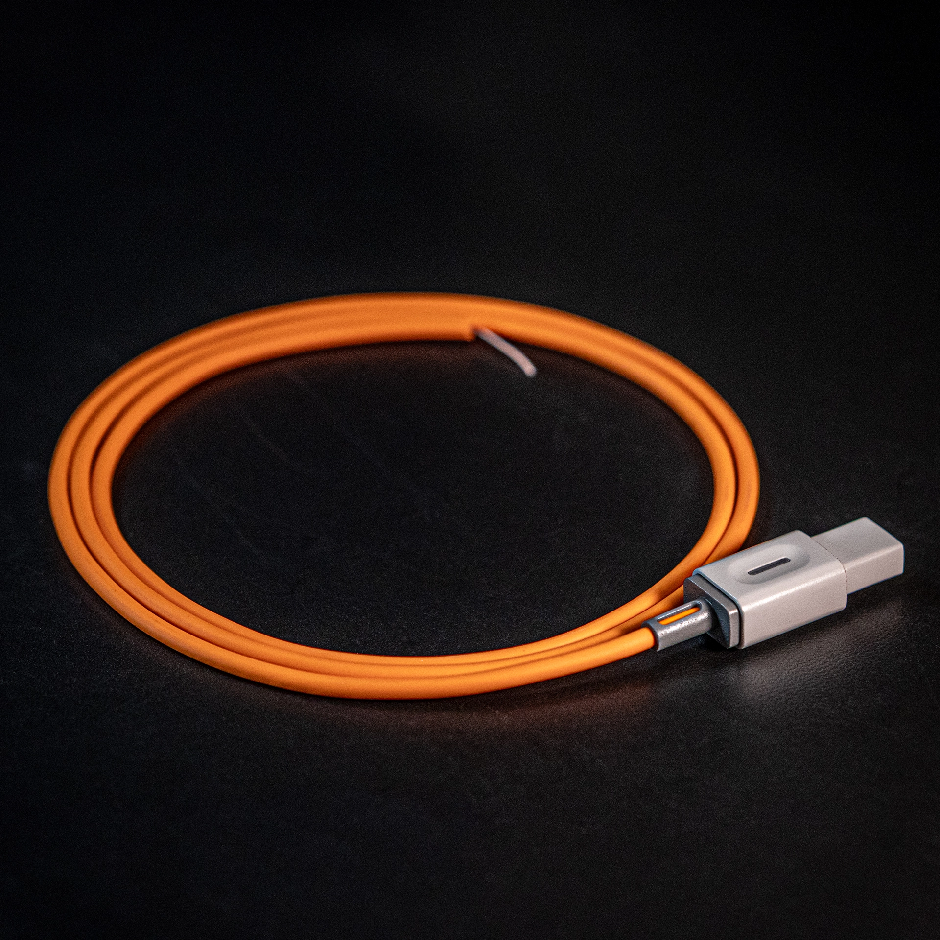 Coiled orange USB-C charging cable with a gray connector on a dark surface.