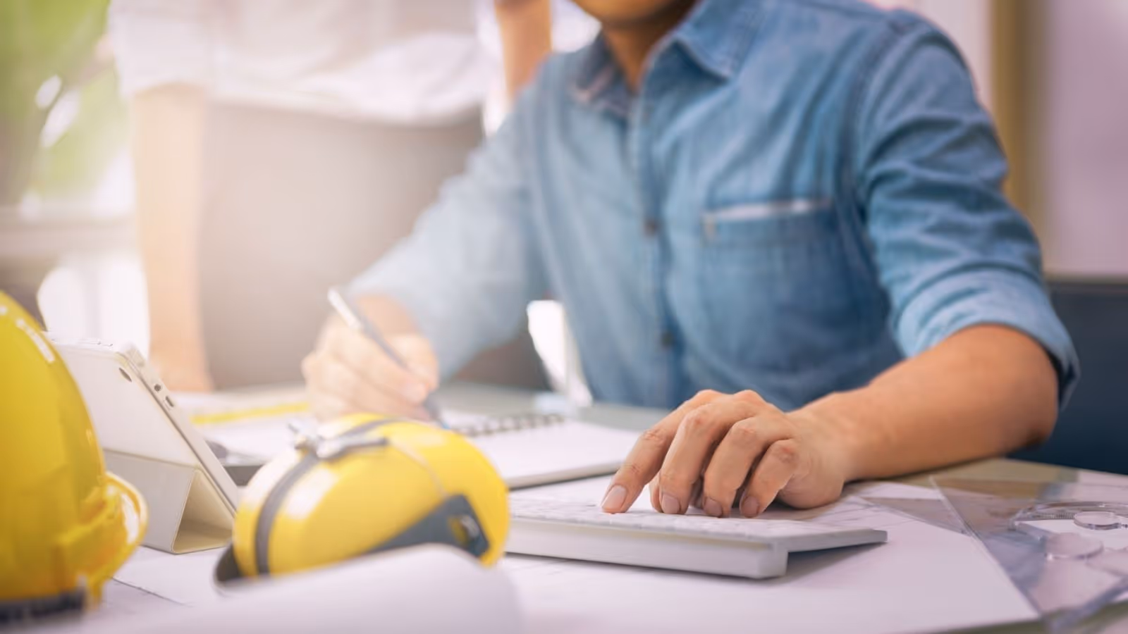 man wearing blue shirt working at his desk on his desktop computer doing payroll