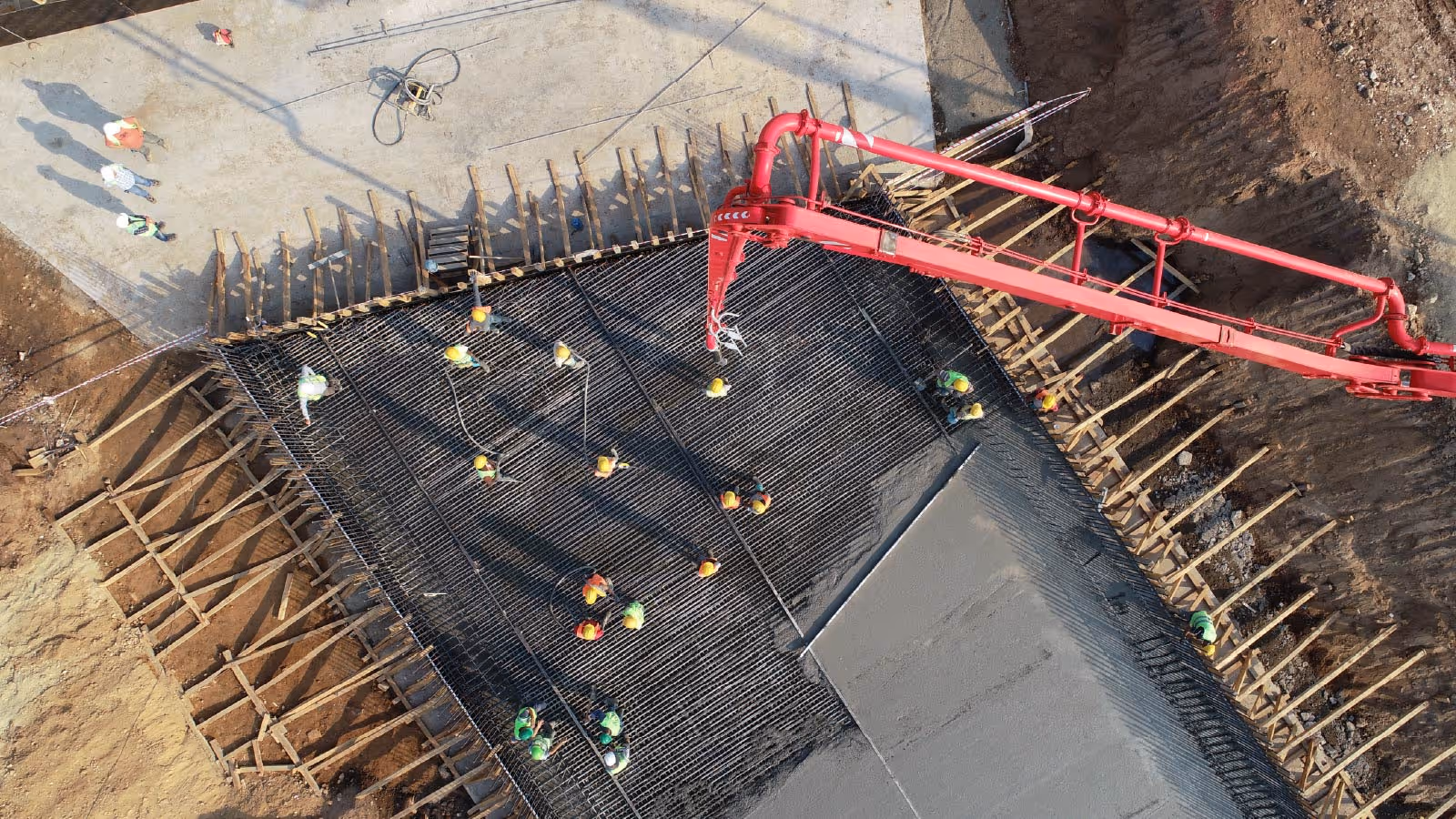 Aerial view of workers pouring concrete with a pump truck over reinforced slab