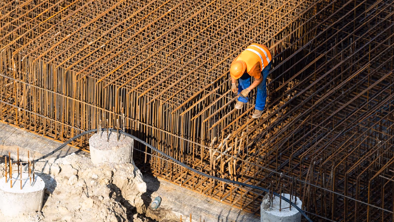 Aerial view of workers pouring concrete with a pump truck over reinforced slab