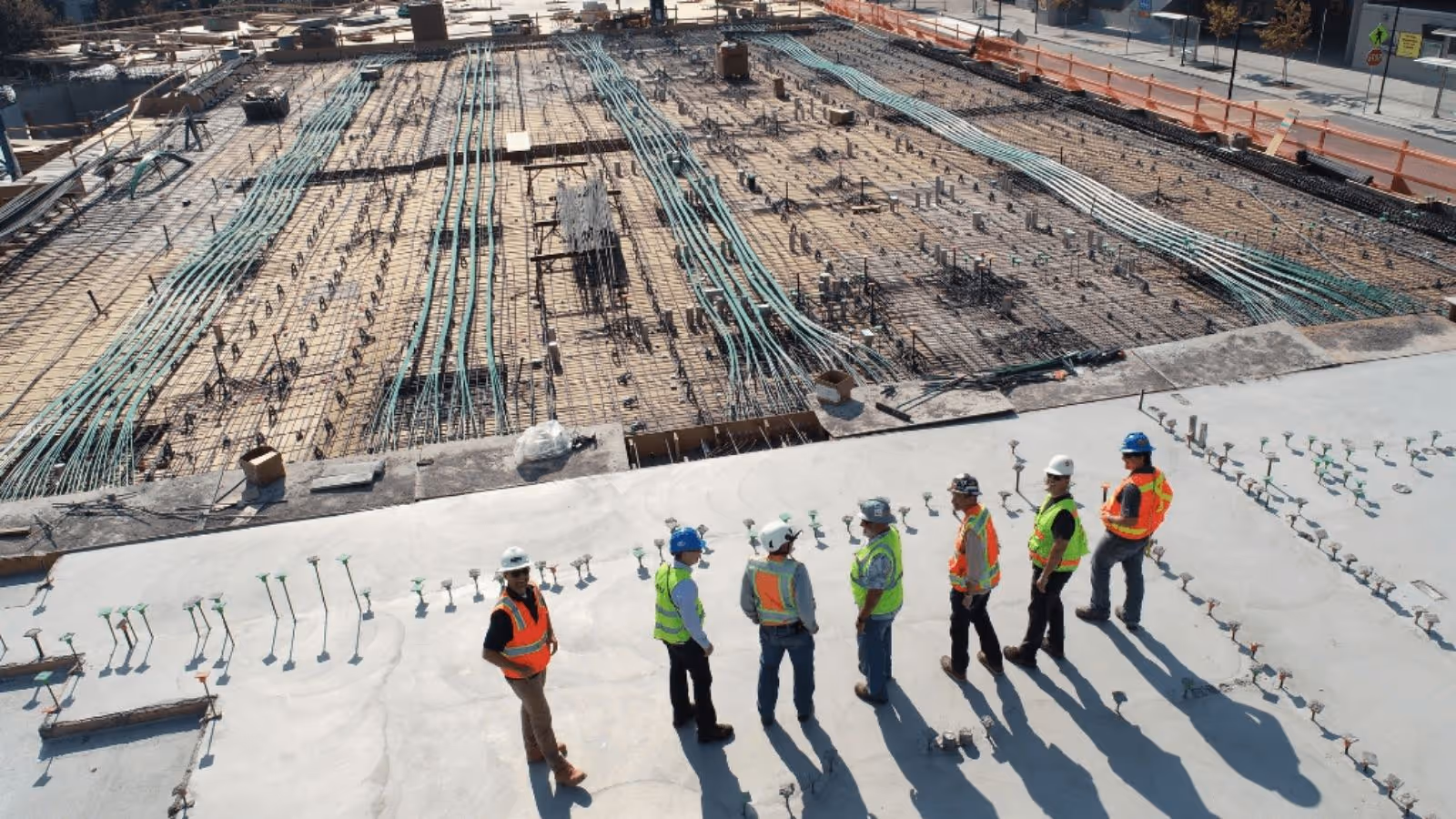 Large inner-city construction site ready for concrete to be poured, with construction workers in high-vis overlooking the site