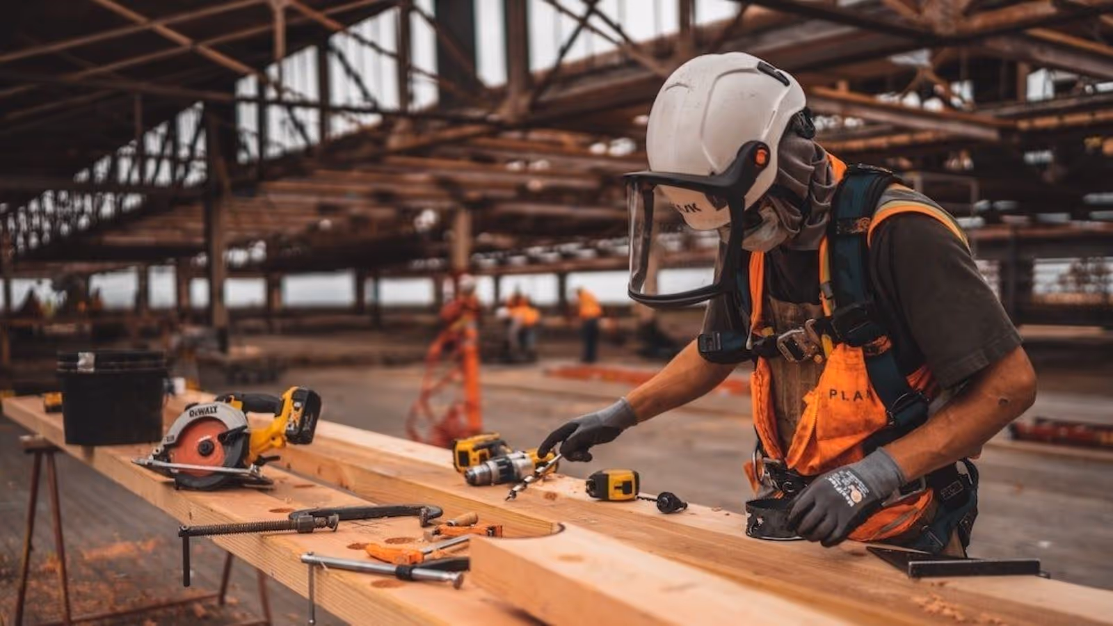 Builder working on wooden blanks with woodworking tools and equipment, wearing safety gear