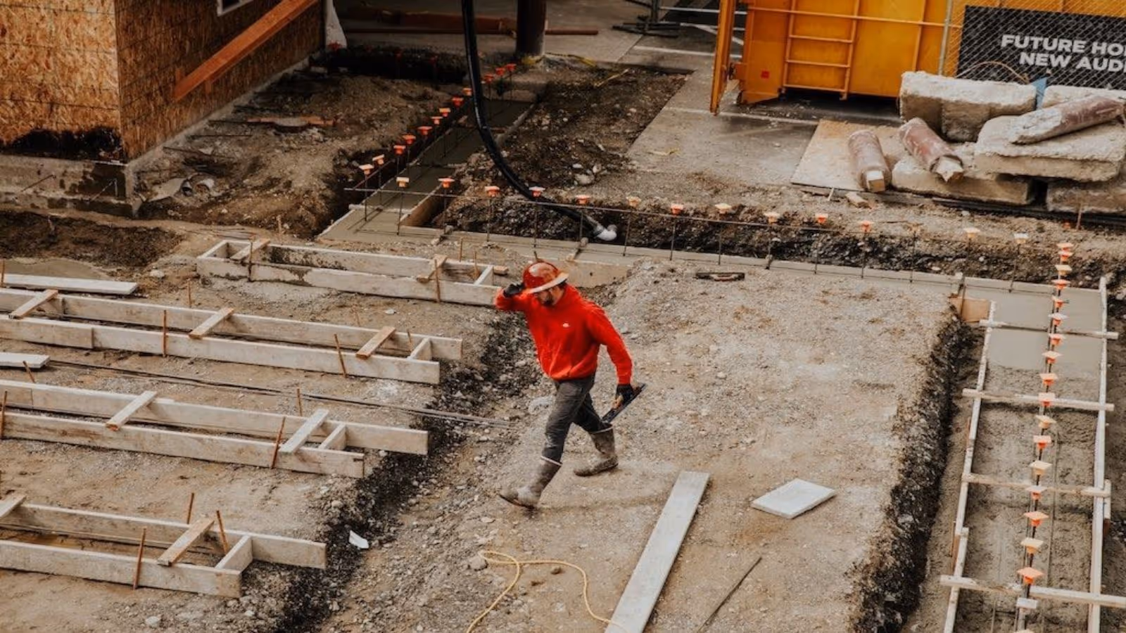 construction worker walking across a construction site, wearing helmet and safety gear