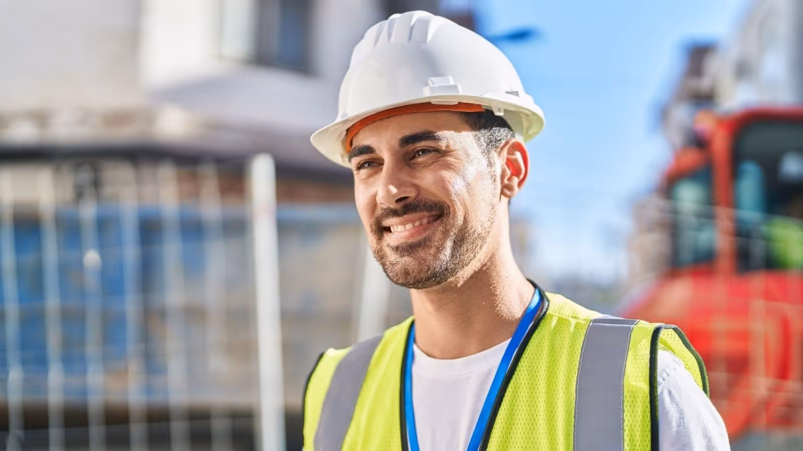 Smiling subcontractor in high vis and safety gear at a construction site