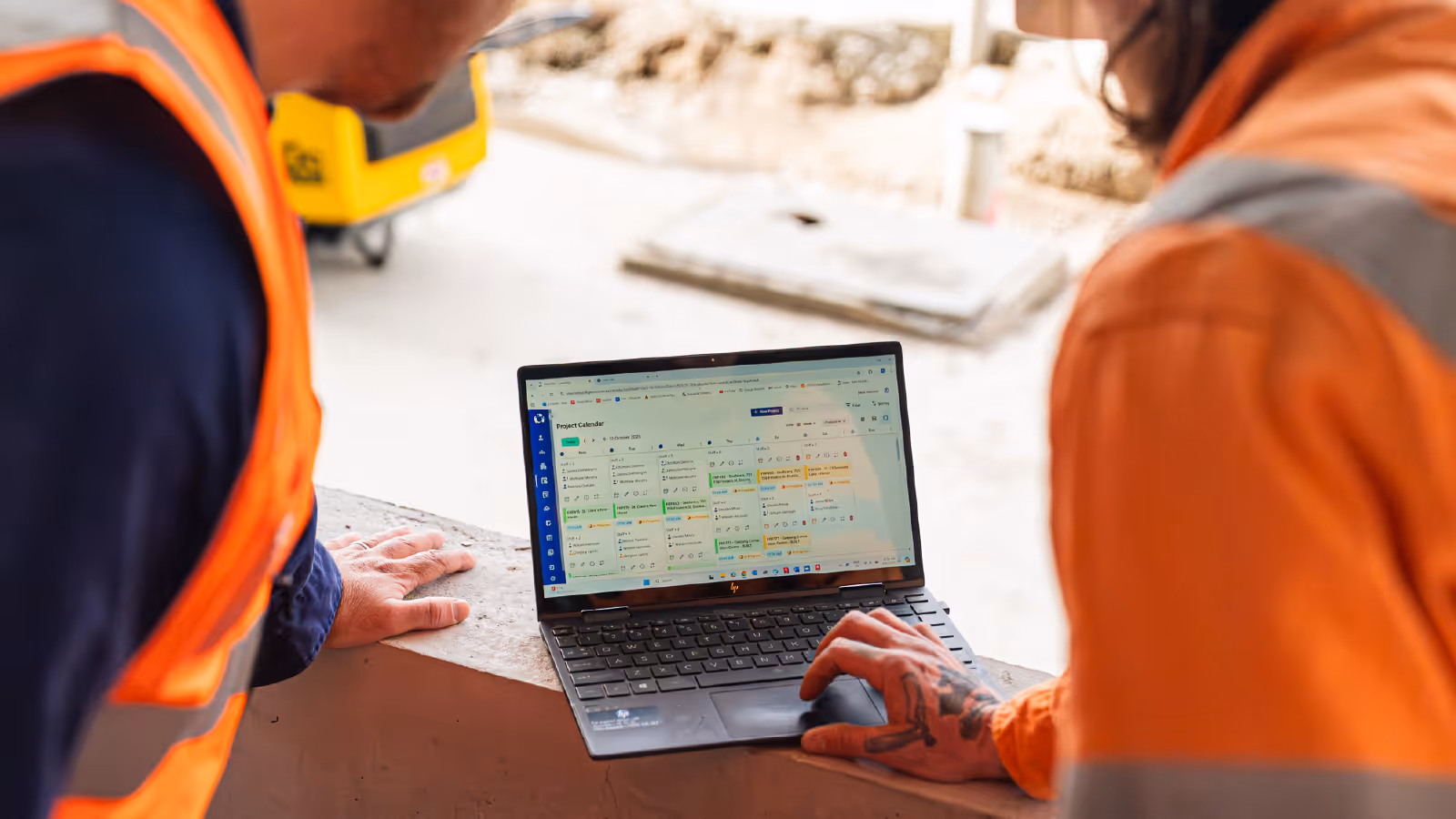 Construction workers reviewing a project schedule on a laptop at a job site using Neo software