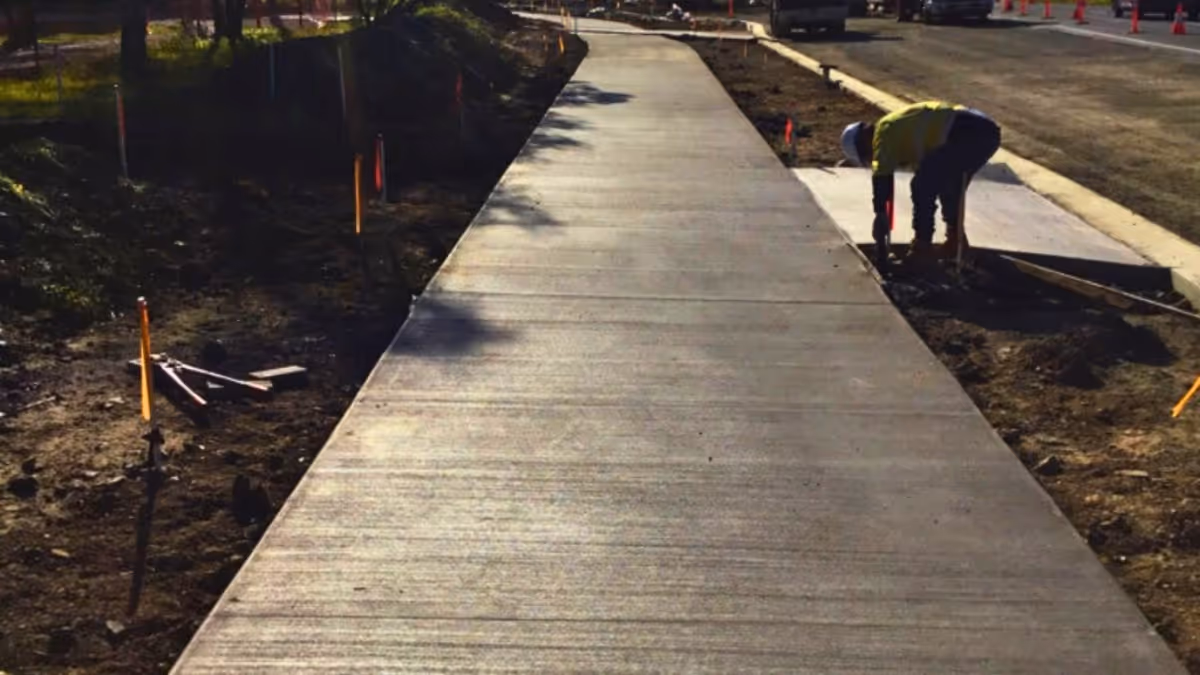 SDC Group staff member working at a freshly poured concrete footpath along a road