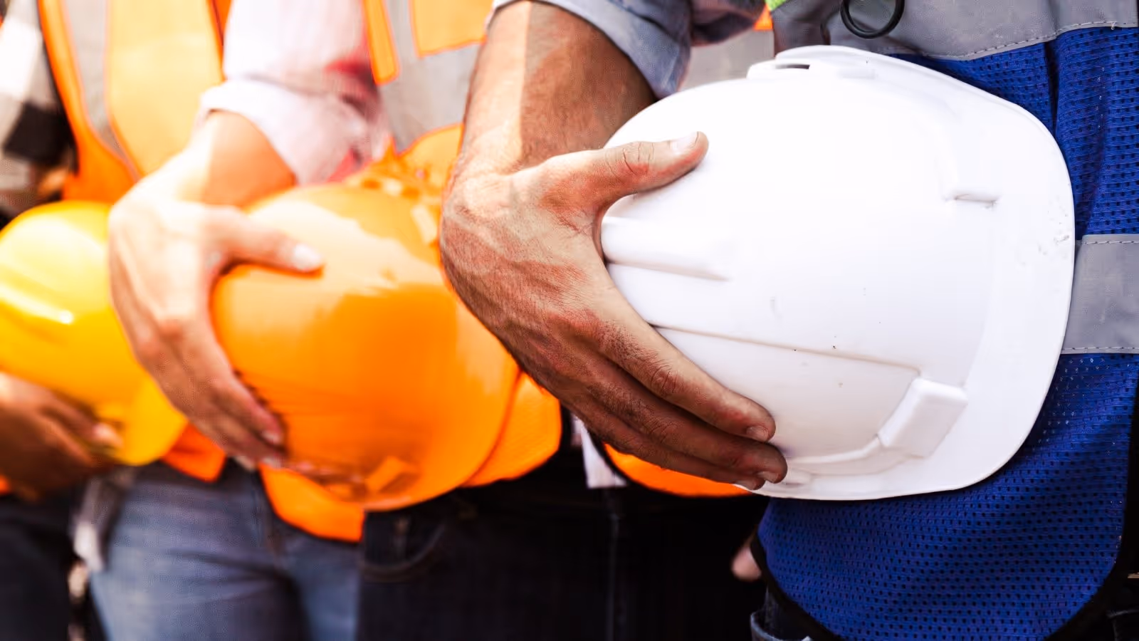 construction workers standing in line wearing high-vis and holding their helmets in their hand