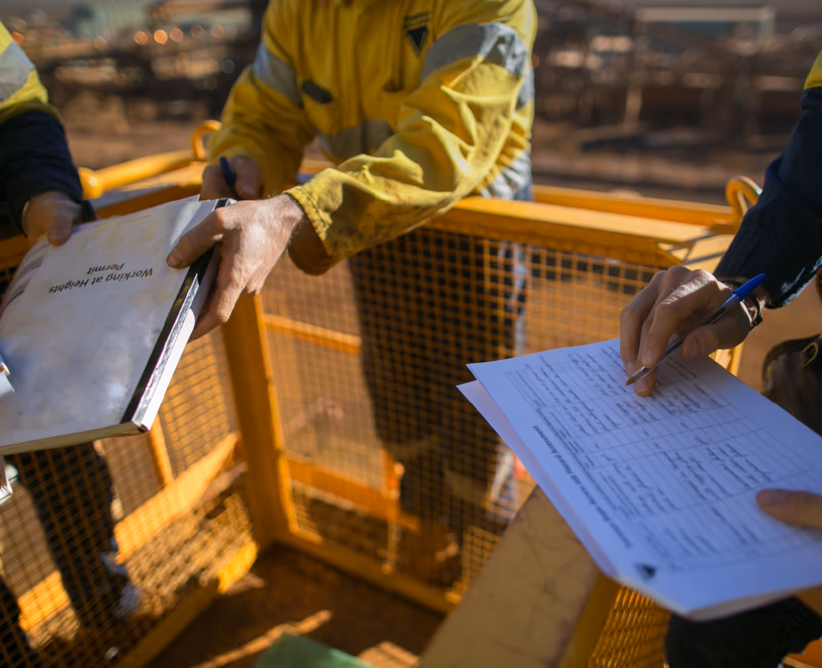 Workers completing safety or compliance forms on a construction site platform