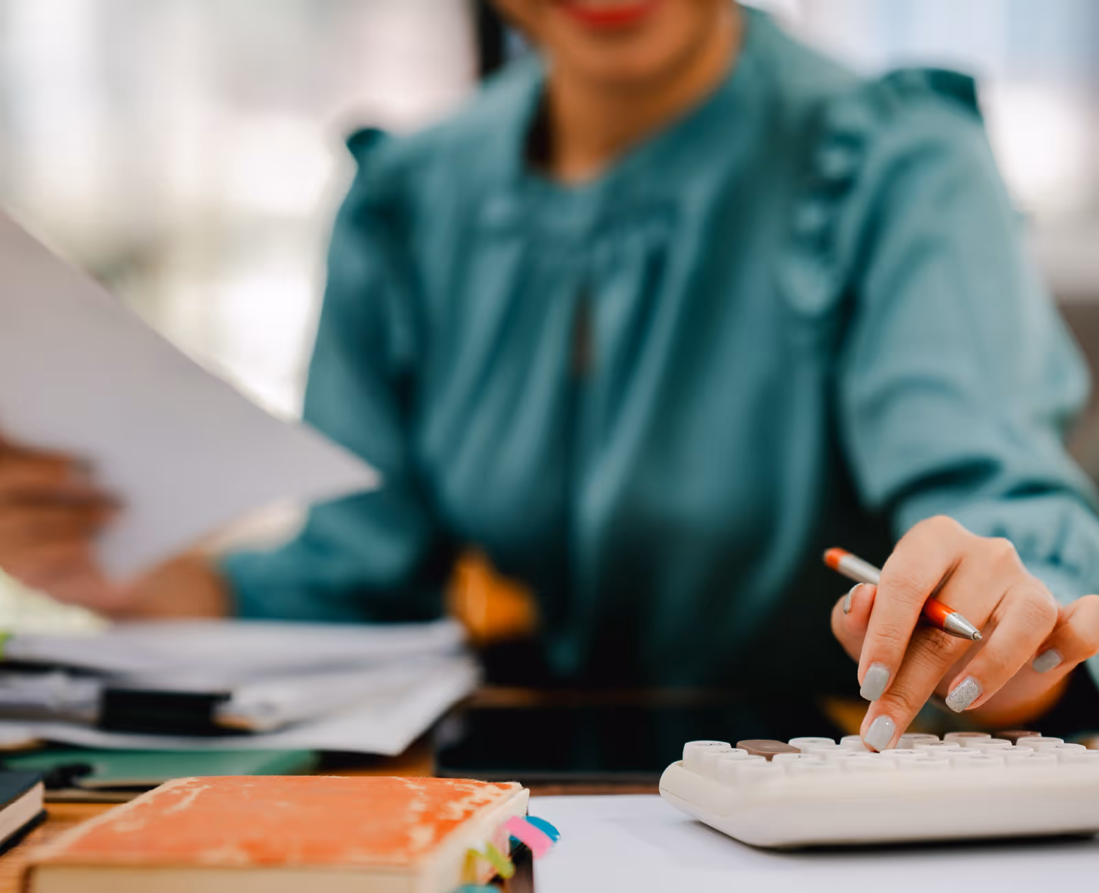 Payroll or accounts staff member calculating figures with a calculator and paperwork