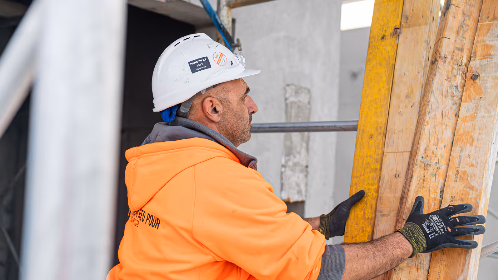 Construction worker installing timber formwork panels for concrete structure