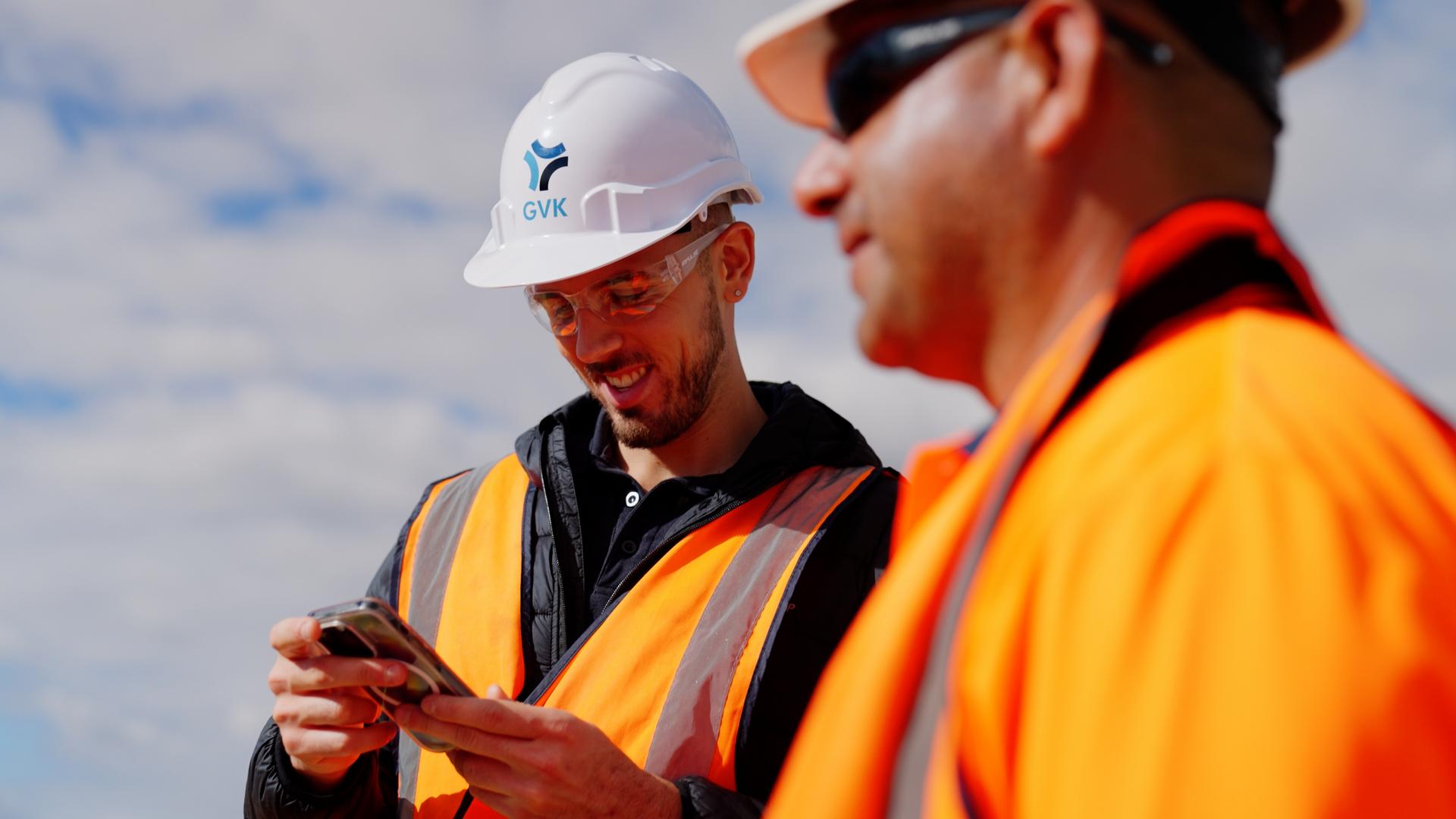Two site supervisors, with one using a mobile phone.