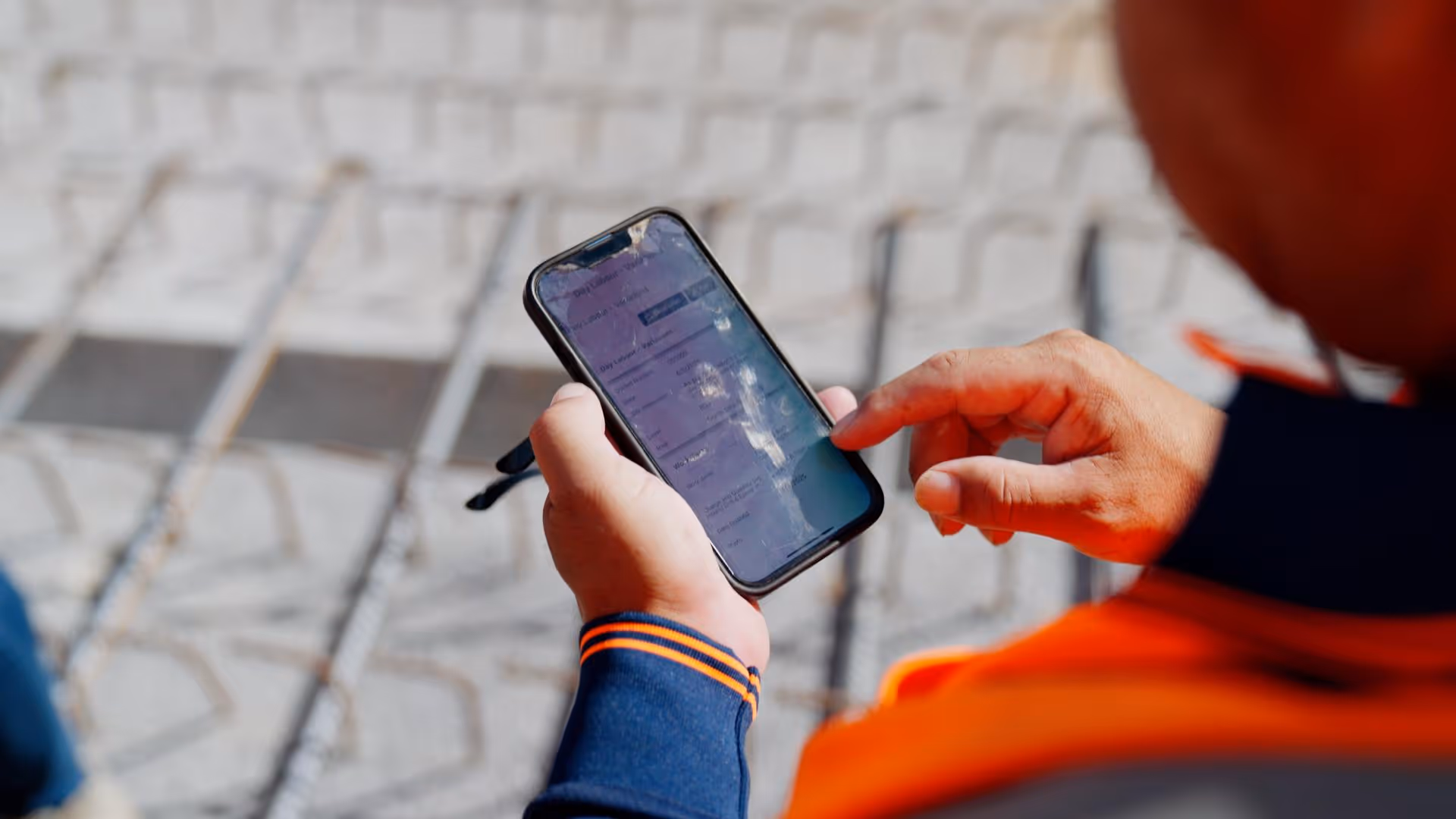 A worker in hi-viz clothing looking at the Neo Intelligence mobile app on their phone, whilst on site.