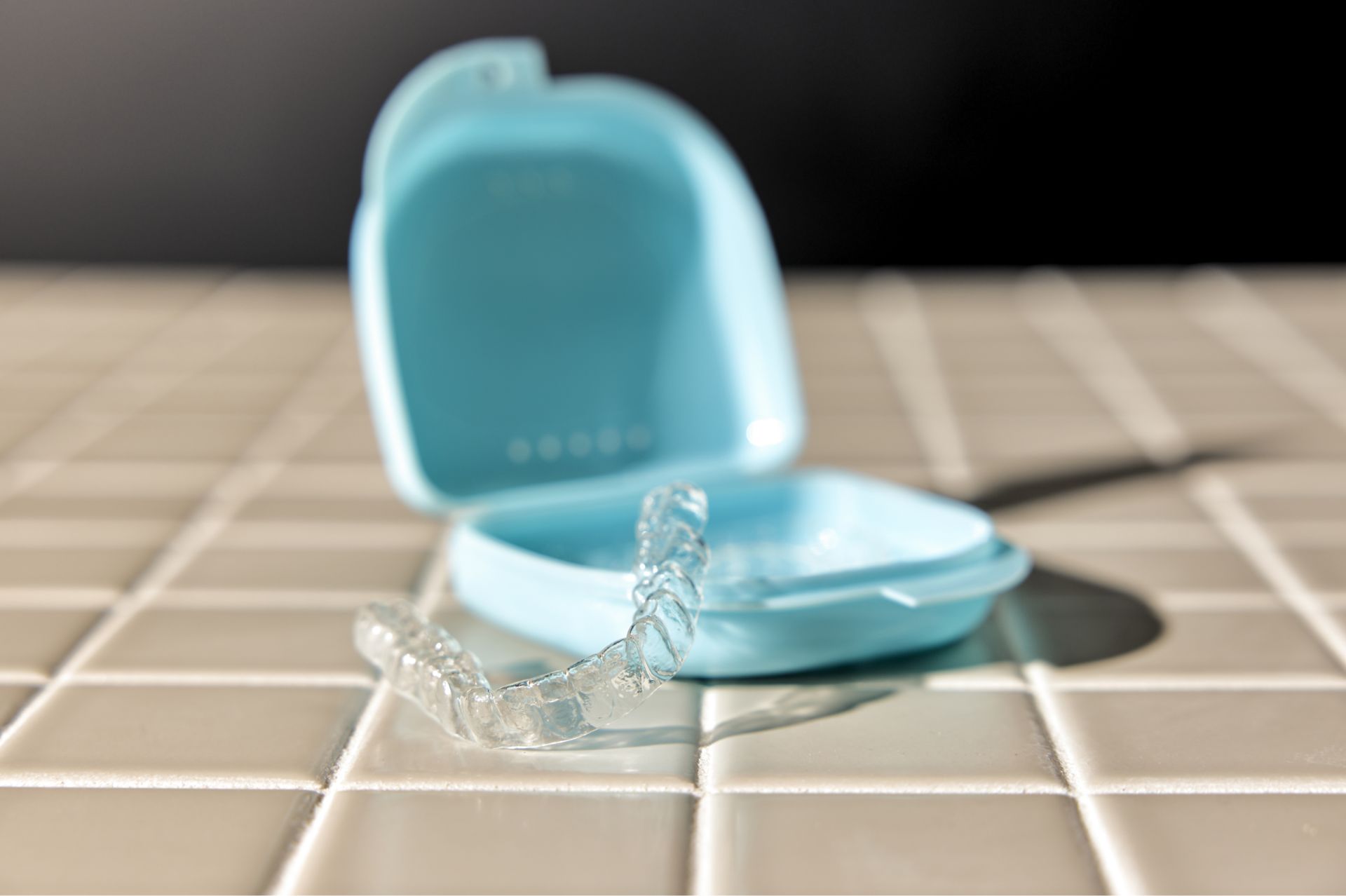 Hand wearing a blue glove pointing at a dental X-ray showing teeth and jawbone with braces.