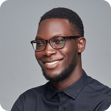 Smiling young Black man with glasses and a beard wearing a dark button-up shirt.