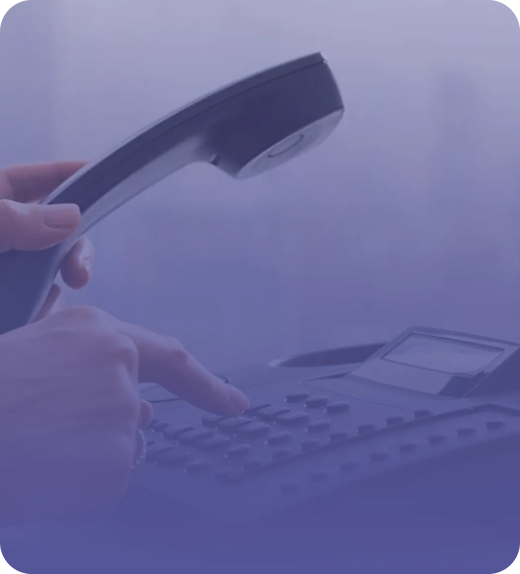 Hand holding a phone receiver while pressing buttons on a telephone keypad.