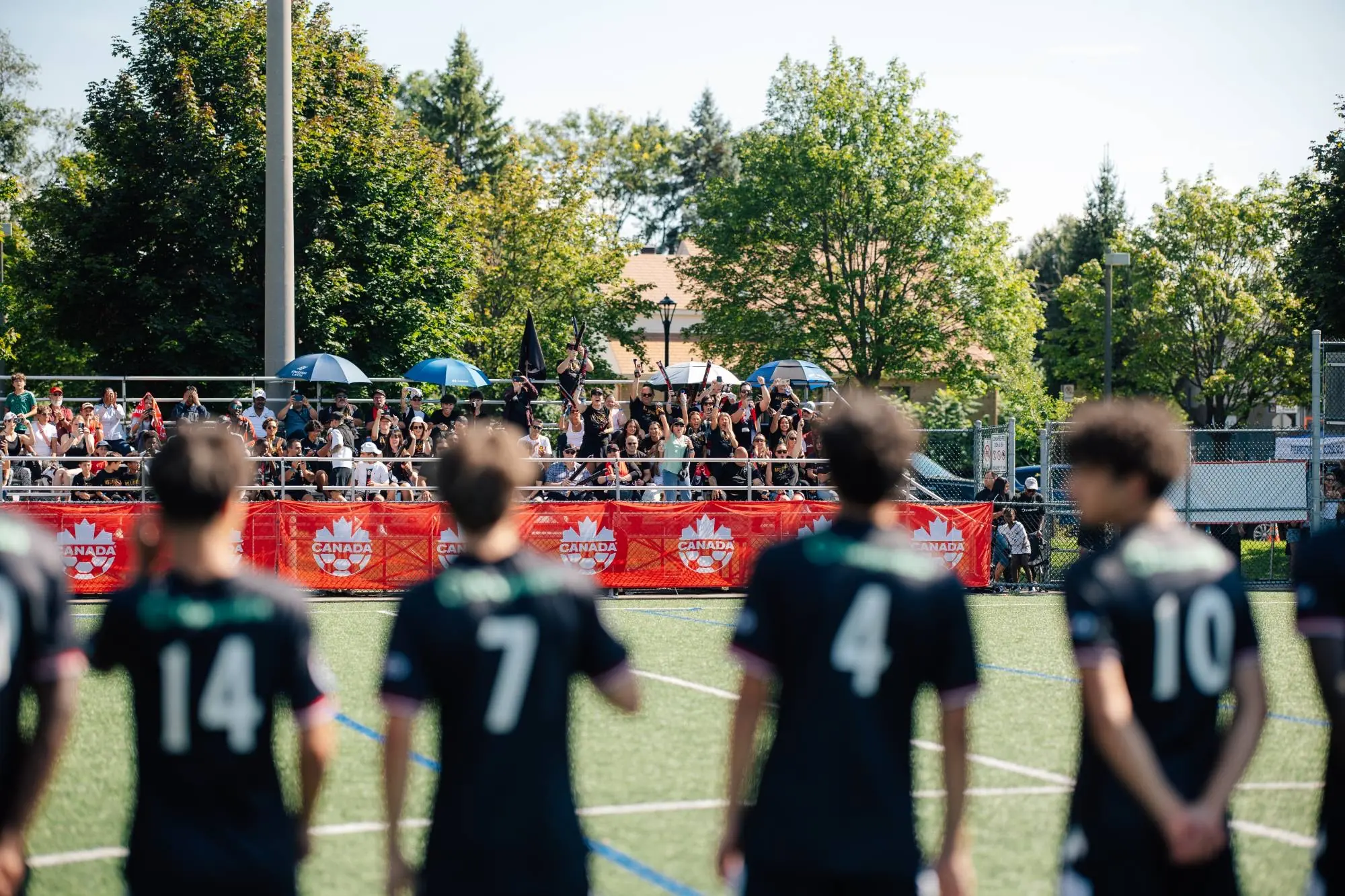 Joueurs de l’AS Laval alignés de dos devant les estrades où les partisans du club les encouragent