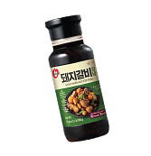 Bottle of Korean pork rib marinade sauce with green label showing cooked pork dish.