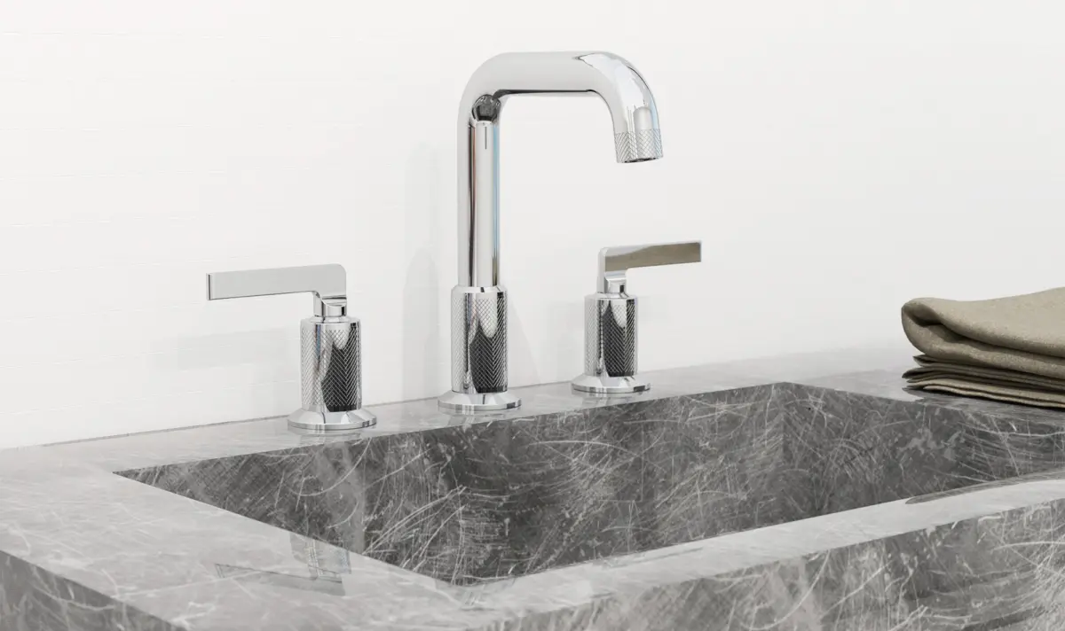 Modern gray marble sink with chrome faucet and two lever handles, next to folded beige towels.