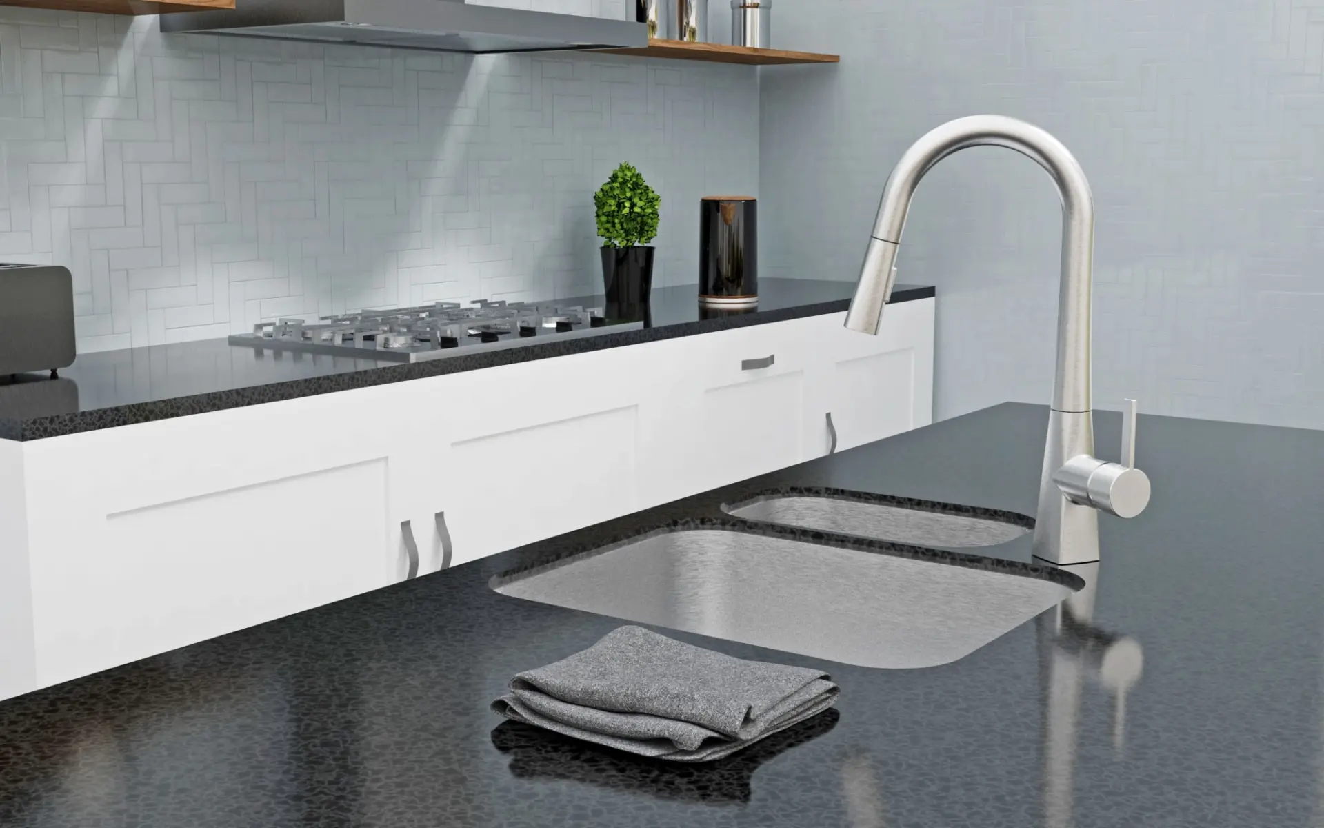 Modern kitchen countertop with dual stainless steel sinks, silver faucet, folded gray cloth, and stove in the background.
