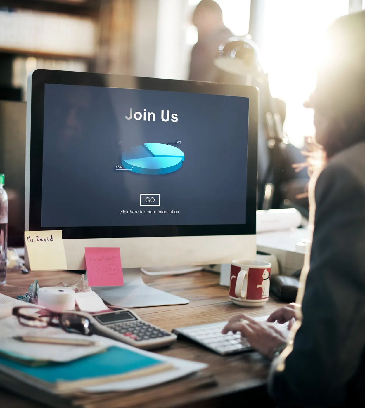 Computer monitor on a busy desk showing a dark “Join Us” signup screen.