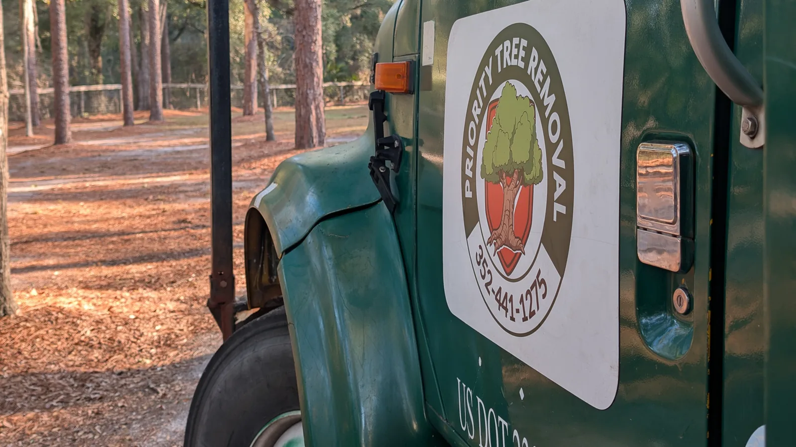 Priority Tree Removal branded green bucket truck with company logo.