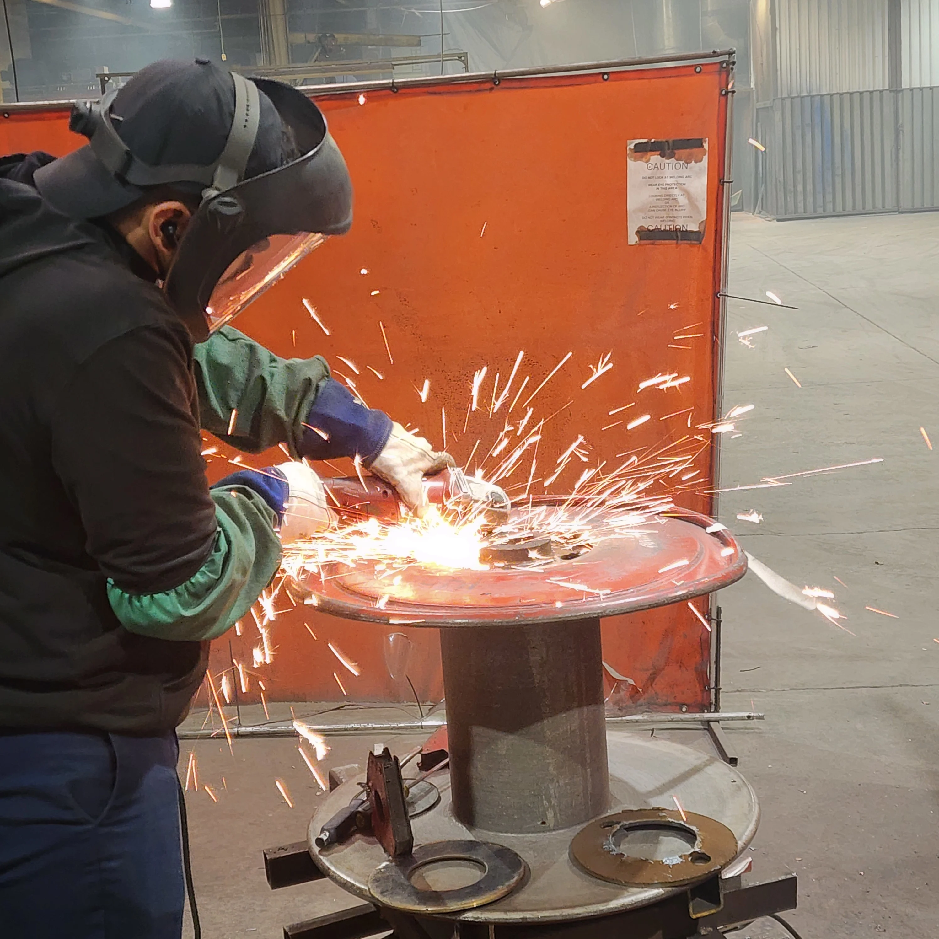 Skilled technician repairing damaged steel wire reel with precision welding and fabrication equipment