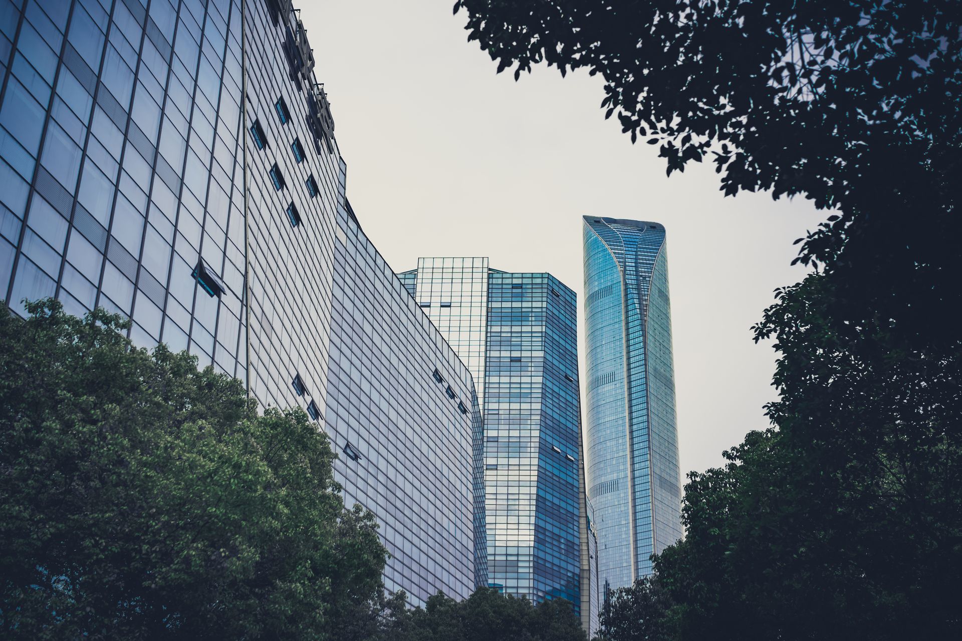 Moderne Bürogebäude mit Glasfassade und grünen Bäumen als Symbolbild für ESG-Kriterien in der Immobilienfinanzierung