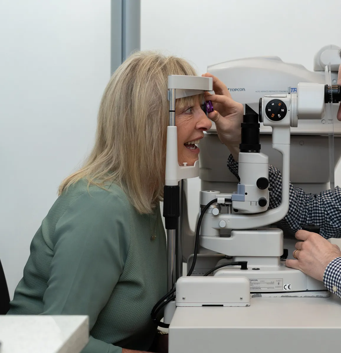 Optometrist conducting an eye examination on a female patient using a slit lamp in a clinical setting.