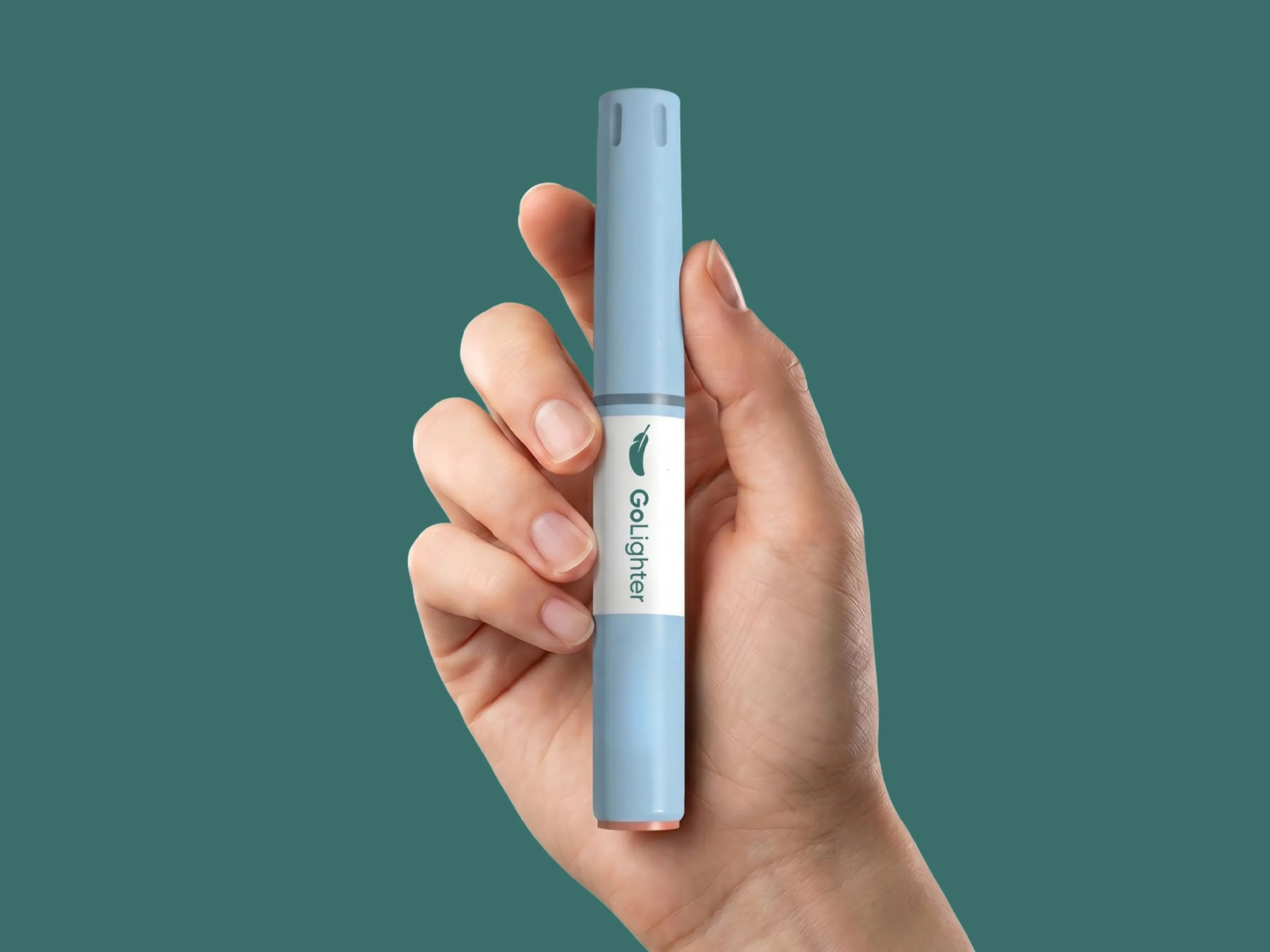 Stylo injecteur bleu GoLighter tenu dans une main, sur fond vert foncé.