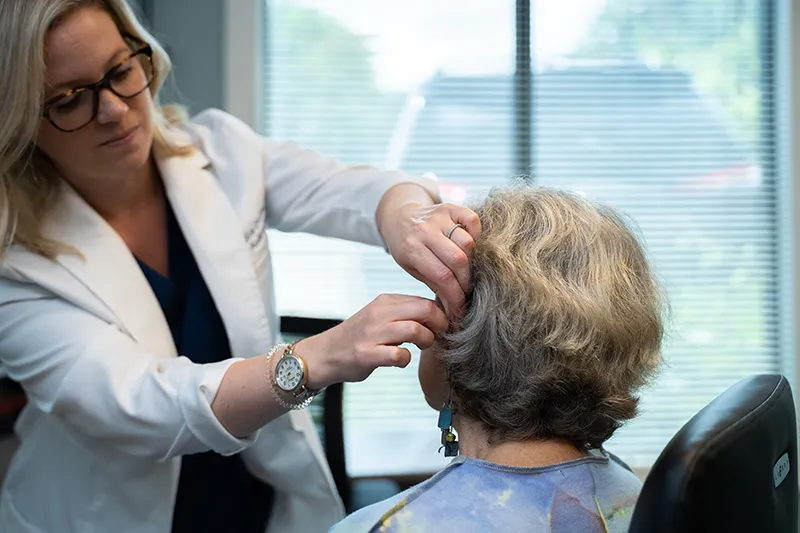 Audiologist fitting a hearing aid in an office