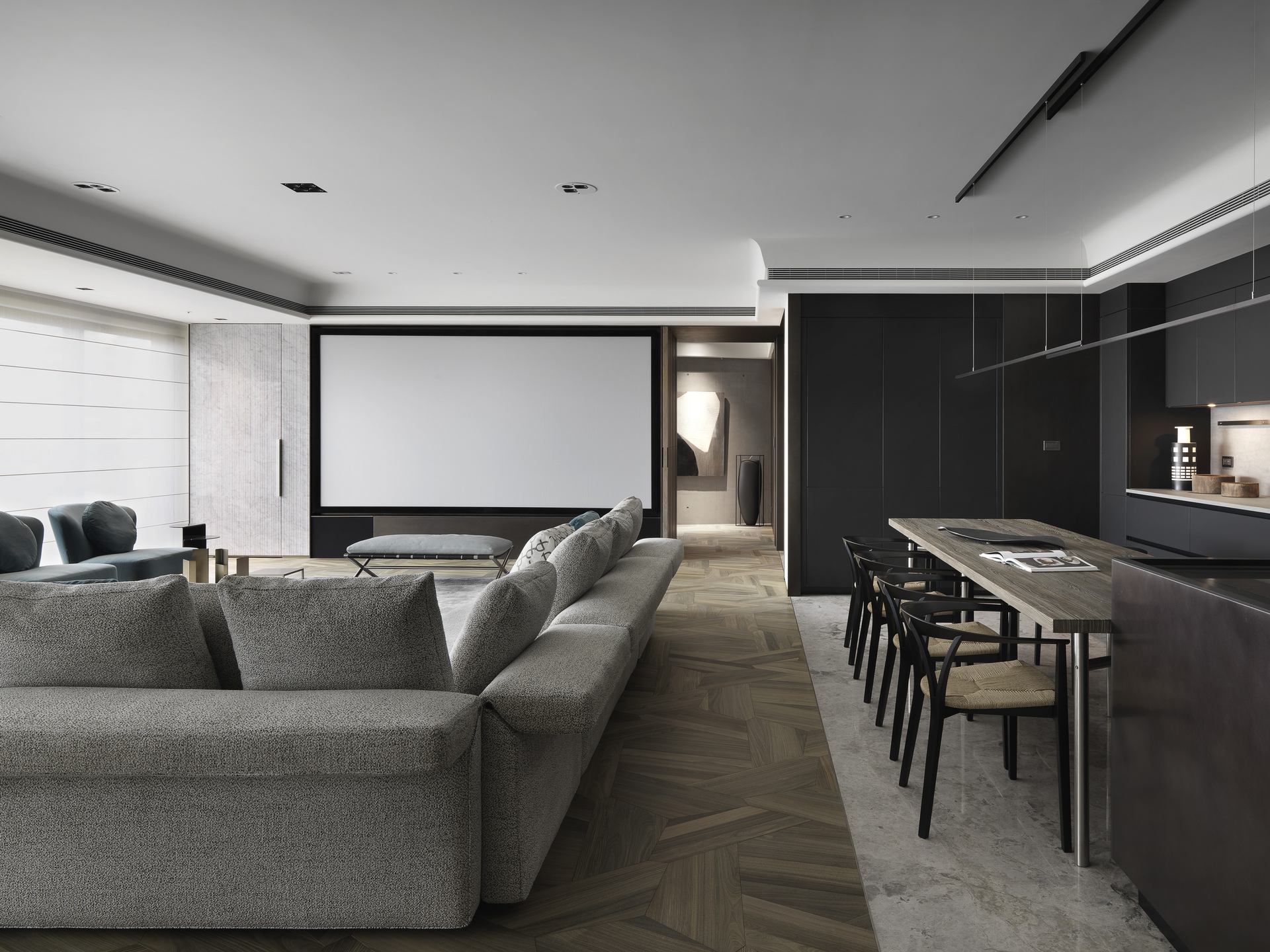 珥本設計｜丽格 III 住宅公領域主敘事：MINOTTI 灰色 L 形沙發與 Barcelona Chair 長凳並置，投影布幕嵌於中景牆體，右側 BOFFI 黑色整面廚具搭風化橡木長桌與 Wishbone 黑椅，玉檀香木地板貫穿全景