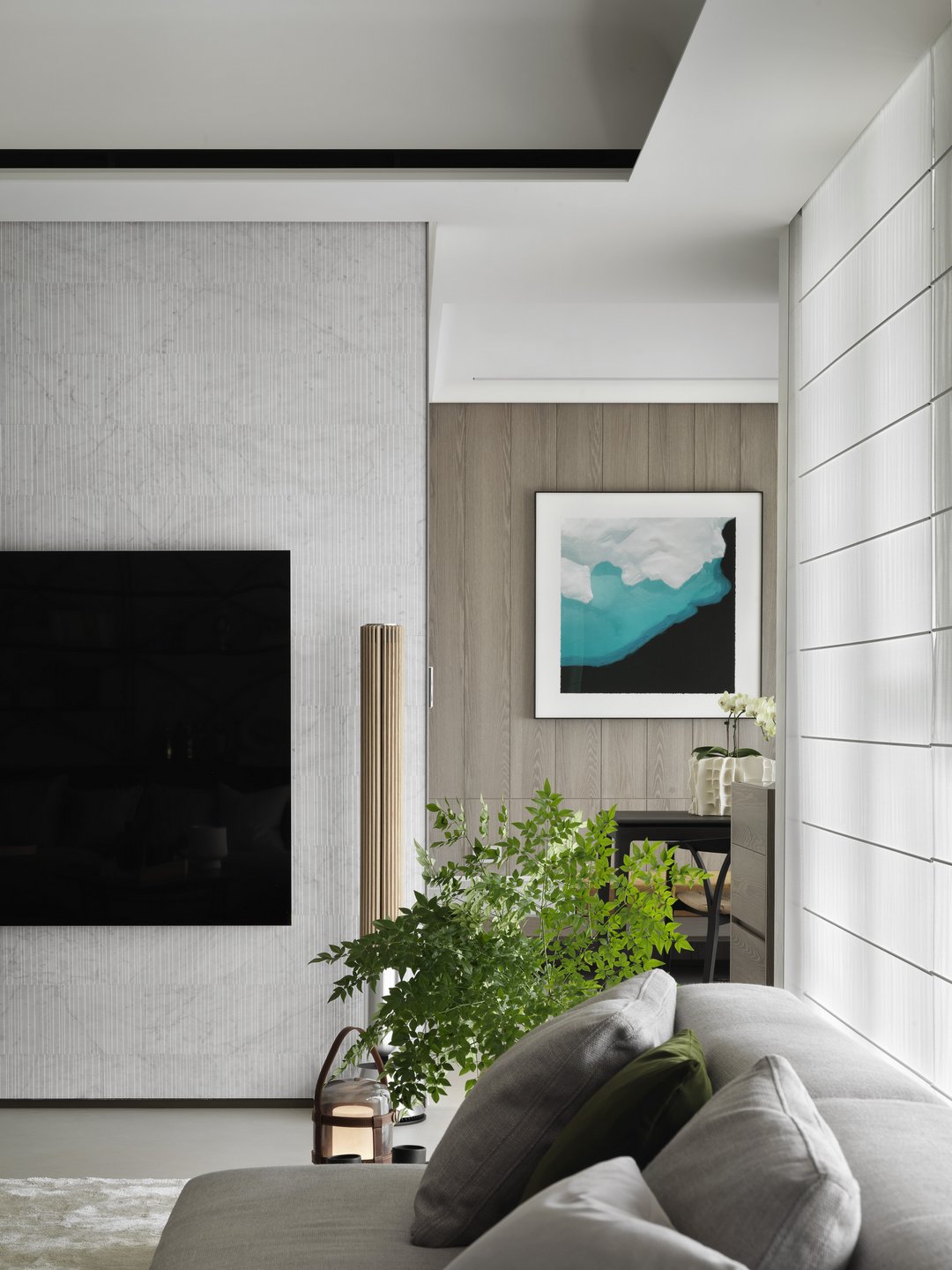 珥本設計|BOFFI HOME II 客廳電視牆特寫:SALVATORI細直紋白色大理石電視牆與木皮牆並置,上方藍綠抽象水彩畫作點題,金屬柱燈與長虹玻璃拉門收出細膩層次