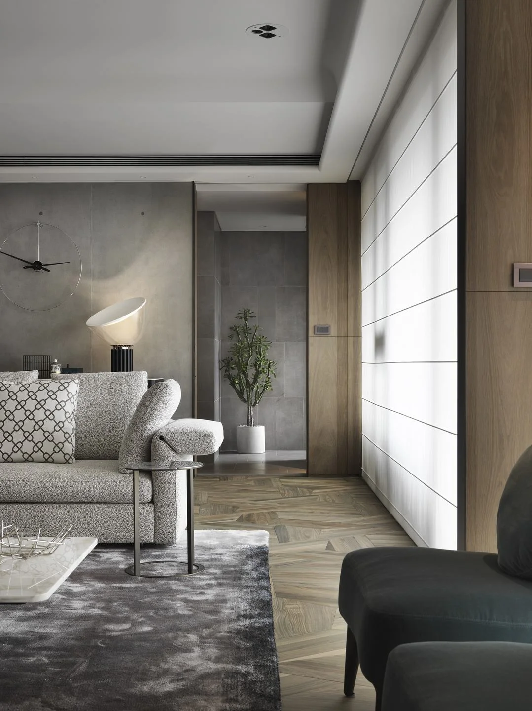 珥本設計｜丽格 III 住宅客廳側景：MINOTTI 灰色沙發搭菱格紋抱枕與絨面單椅，Nomon 極簡大圓掛鐘與 Flos Taccia 桌燈於灰色清水模牆錨定，深綠絲絨扶手椅坐落於窗邊。