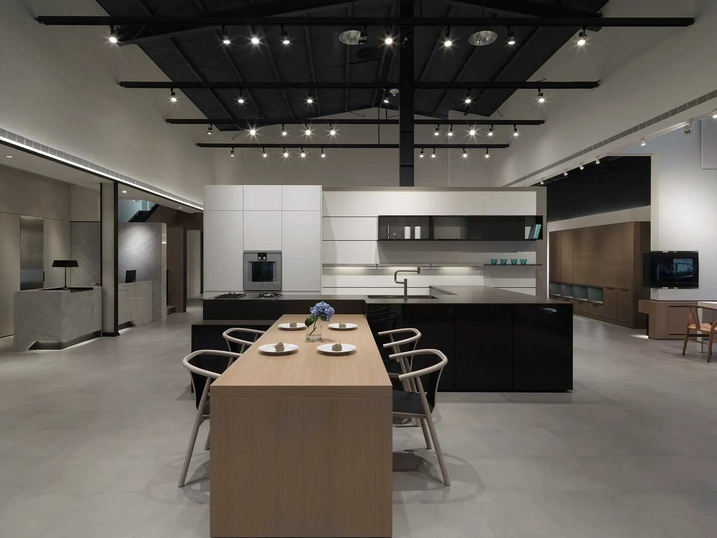 珥本設計｜築韻 LEICHT 廚房展示店挑高全景：黑色烤漆中島廚具搭白色霧面上櫃，木質餐桌與中島串聯多場景動線
