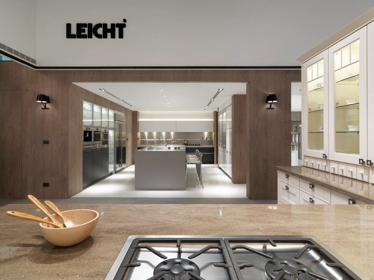 珥本設計｜築韻 LEICHT 廚房展示店品牌入口動線：石材檯面瓦斯爐為前景，LEICHT 招牌下木質展示區銜接古典風格廚具