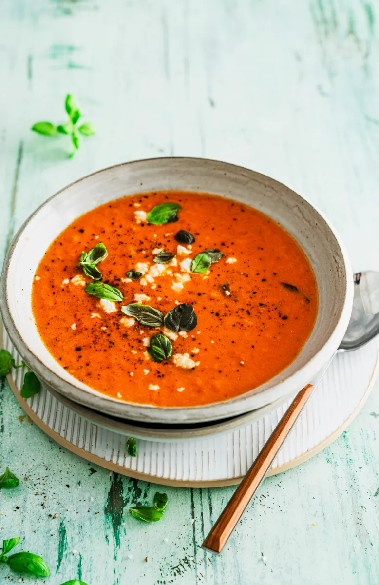 Plate of meatballs in creamy orange sauce with bell peppers and parsley, accompanied by bowls of lettuce and gnocchi.