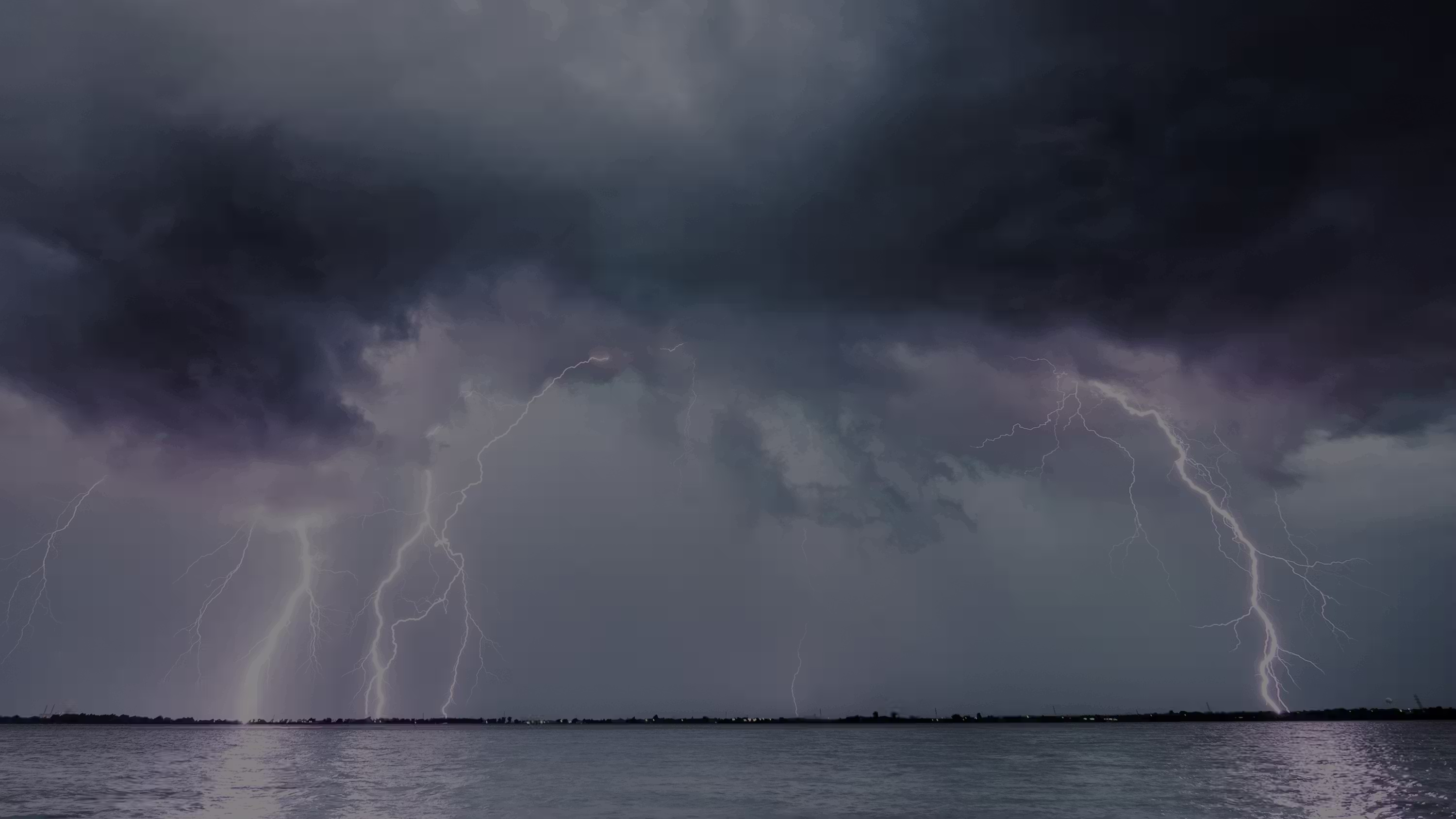 Bouřkové mraky a několik blesků zasahujících jezero za temné a bouřlivé noci.