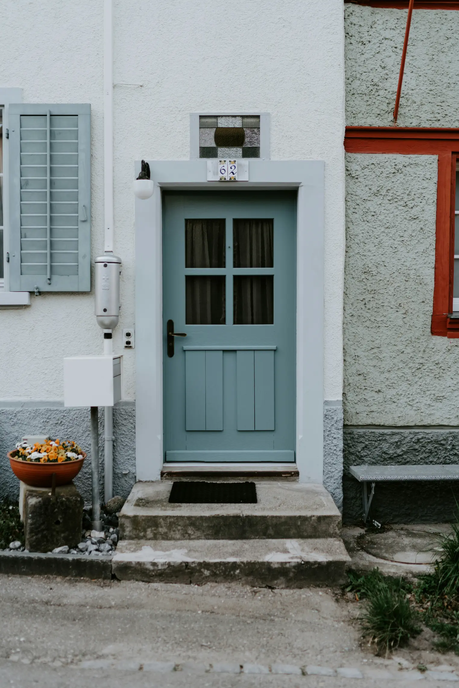 Closed beige panel door with silver handle in a white wall, flanked by green plants and wooden floor.