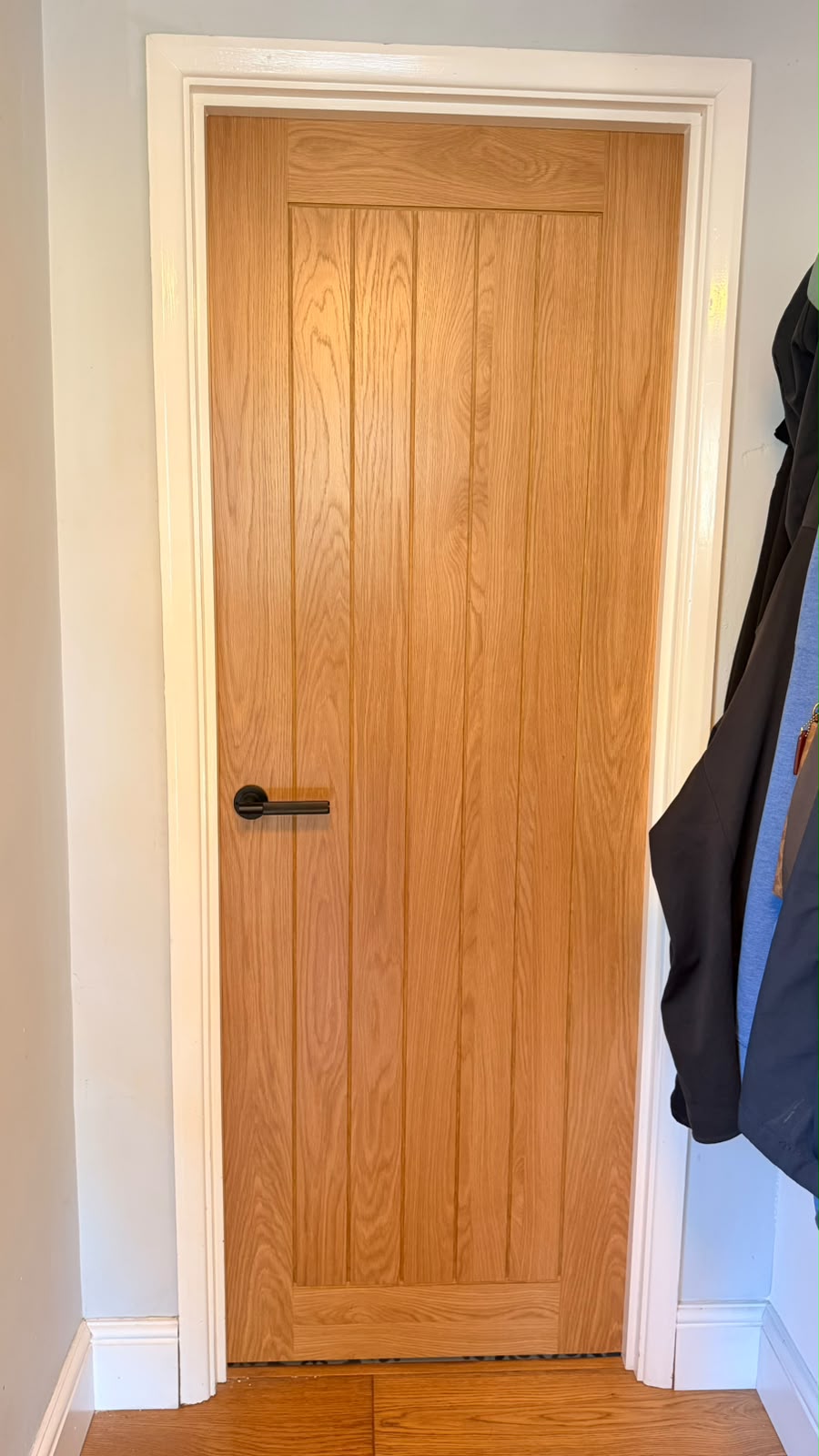 Fully finished oak cottage internal door beside coat hooks in Bordon