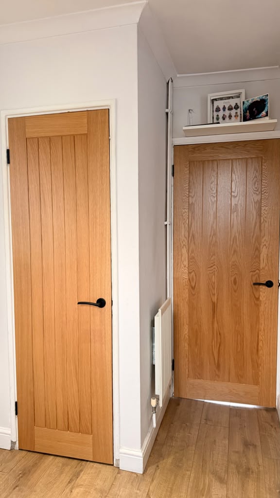 Two Holdenby Oak internal doors with black lever handles above timber flooring in Woking
