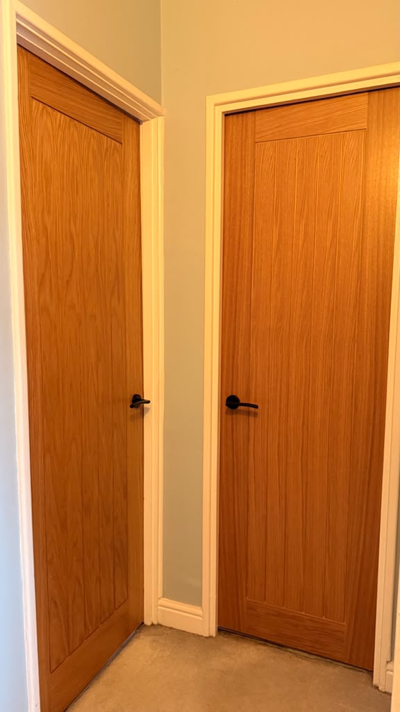 Two Holdenby Oak internal doors with black lever handles above carpet in Woking