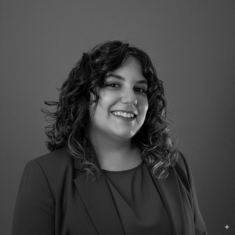 Retrato en blanco y negro de una mujer sonriente con cabello rizado, vistiendo un blazer y blusa.