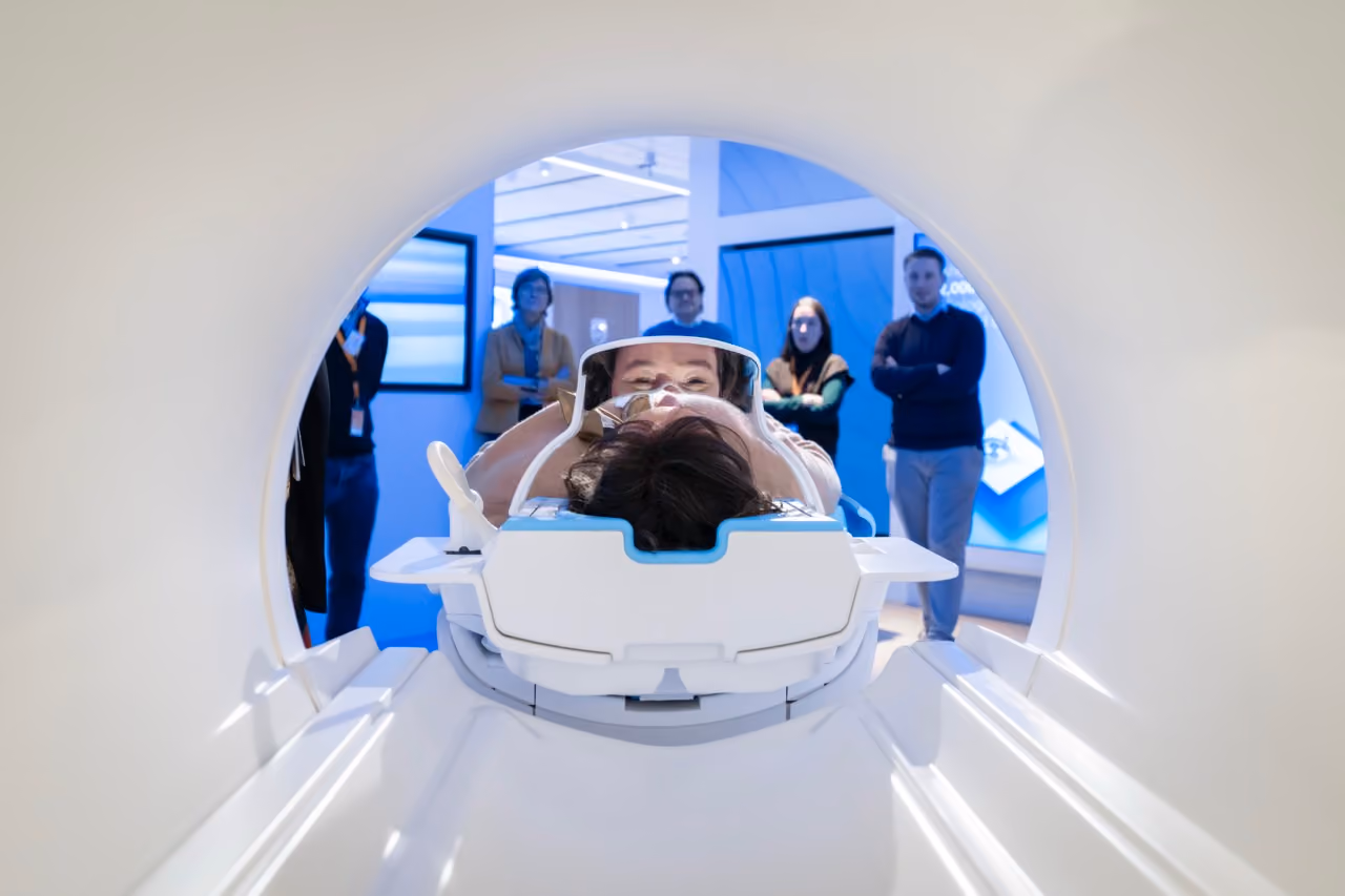 Patient lying face-up inside a CT scanner with medical staff in the background.