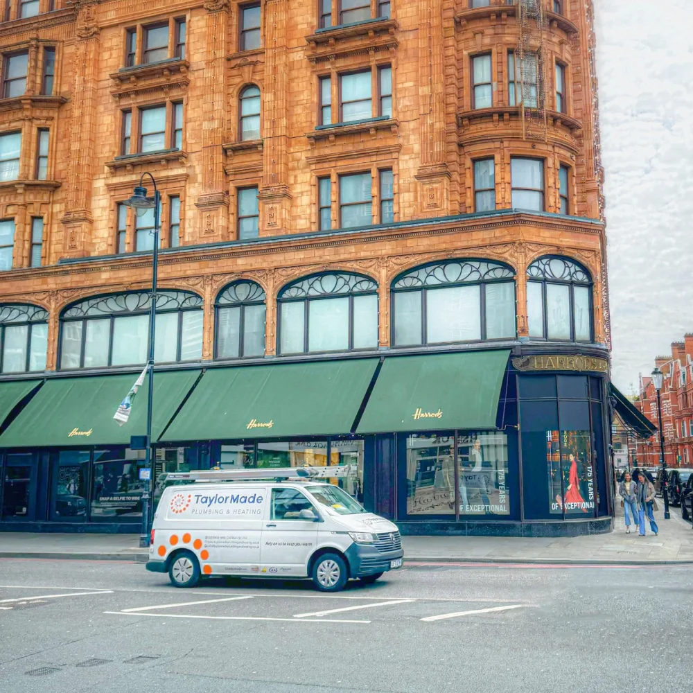 TaylorMade Plumbing van on street in front of Harrods with its distinctive brown building and green awnings.