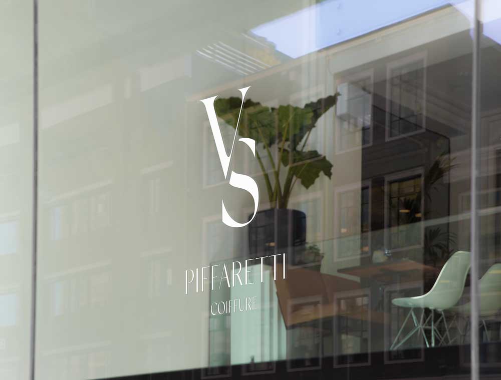 VS Piffaretti Coiffure Logo auf Glasscheibe eines Friseursalons, elegantes weisses Monogramm-Logo mit Serif-Schrift