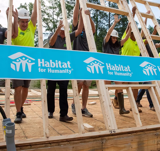 people lifting framed wall 
